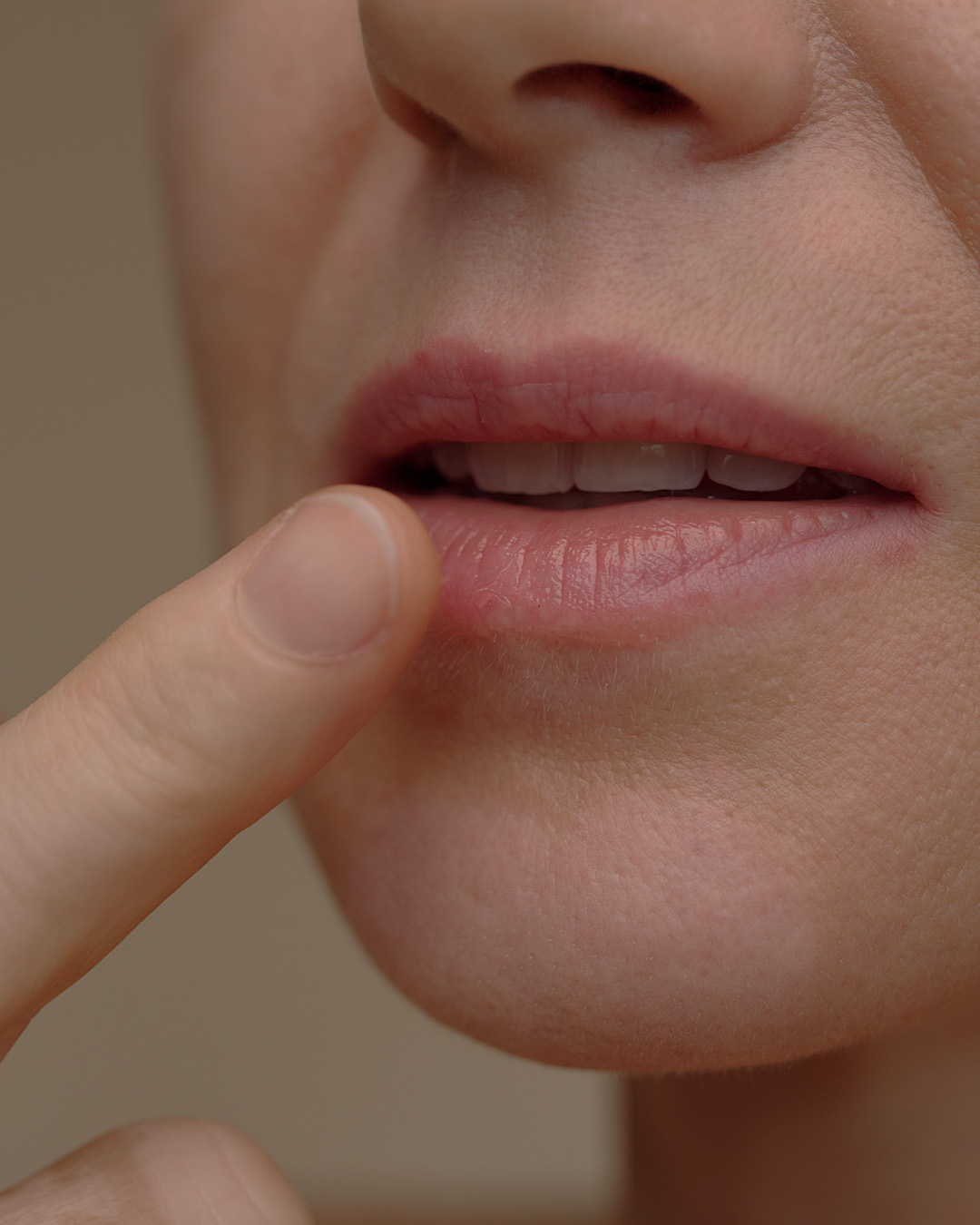 Ein Mensch berührt mit dem Finger kurz seine Lippe.